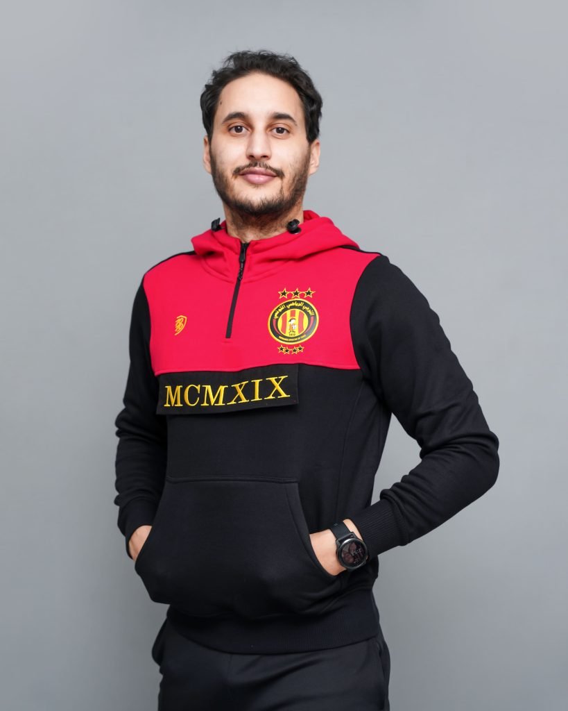 Supporter portant un sweat 1/2 zip Espérance Tunis noir et rouge avec capuche et logo brodé